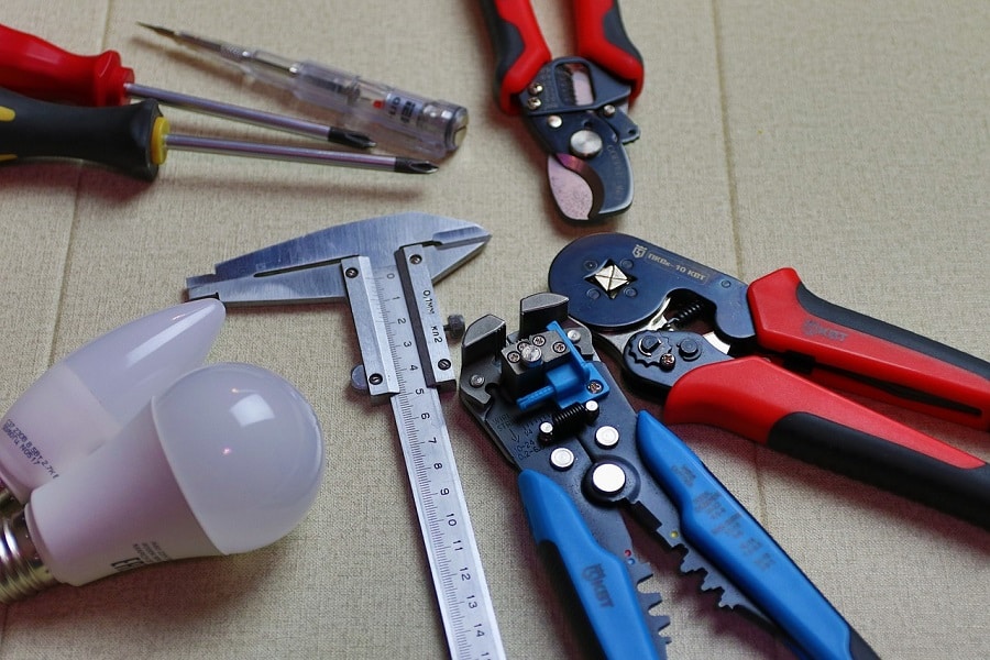 Best Electrical Contractor in Greenacres Close Up of Wire Cutters and Measuring Tools Next to a Light Bulb