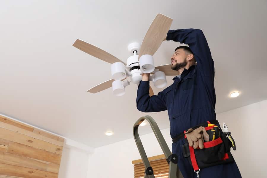 Best Electrician in Greenacres Florida Electrician repairing ceiling fan with lamps indoors. Space for text