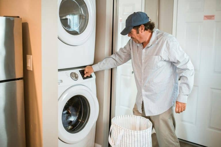 Best Electrician to Install a Whole Home Surge Protector in Boynton Beach A Man Doing Laundry with a Tower Washing and Drying Machine