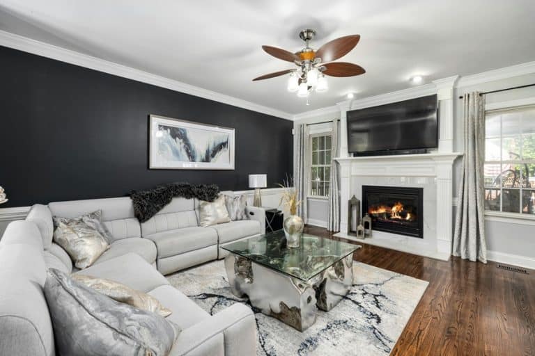 Best Ceiling Fan Installation Electrician in Delray Beach a Living Room with Gray and White Furniture, a Fireplace, a TV and a Ceiling Fan