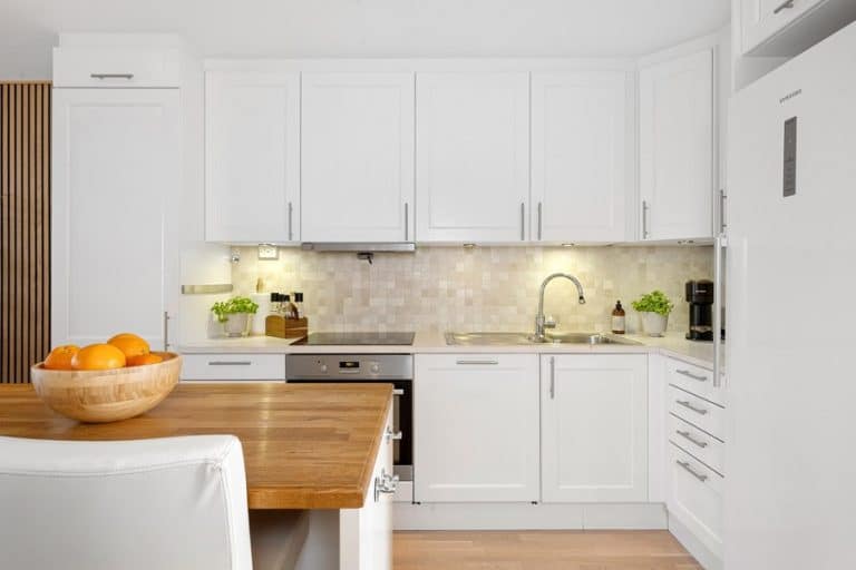 Best Under Cabinet Lighting Electrician in Delray Beach an All White Kitchen with Under Cabinet Lighting and a Bowl of Fruit on a Table in the Center of the Kitchen