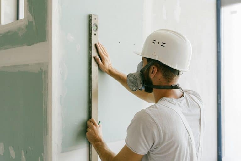 Best Home Remodel Electrician in Boca Raton a Man Wearing a White Hard Hat Holding a Level Against a Wall