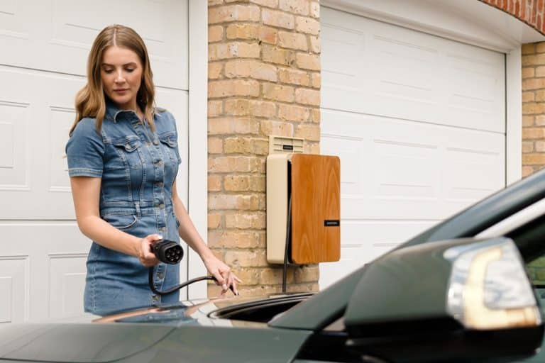 Best EV Charger Installation Electrician in Stuart Florida a Woman Standing in a Driveway Holding an EV Charger in Front of a Black Car