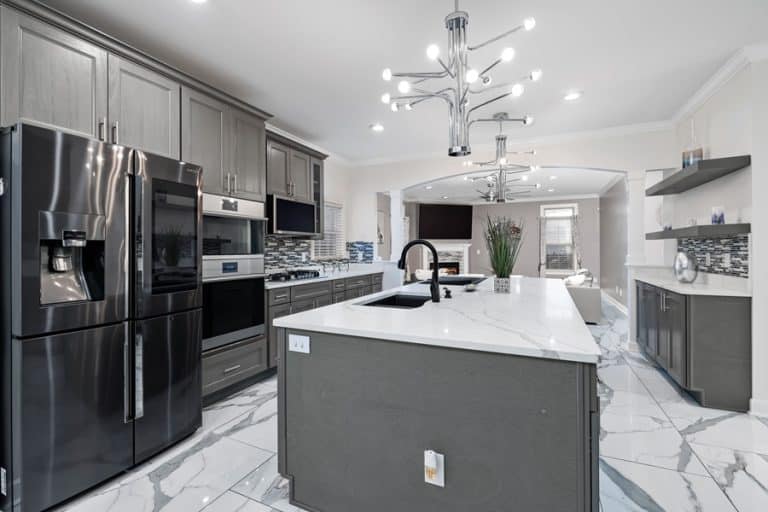 Best Kitchen Remodel Electrician in Jupiter Florida a Luxury Kitchen with Chandeliers Above an Island, Granite Counters, Black Cabinets and White Flooring