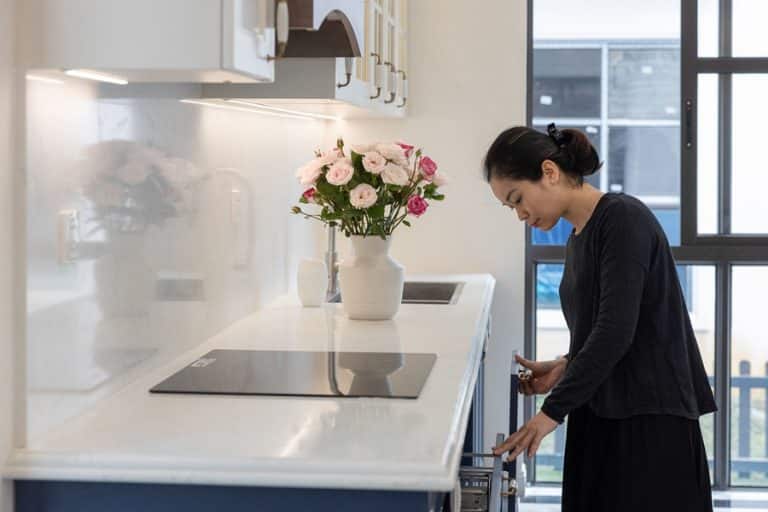 Best Under Cabinet Lighting Electrician in Stuart Florida a Woman Standing in a Kitchen with Flowers in a vase on a counter and under cabinet lighting