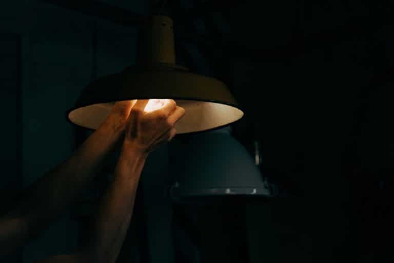 Best Electrician Near Me in North River Shores Florida Close Up of a Person Screwing in a Lightbulb to a Light Fixture